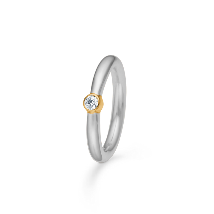Smykke ring i sølvfarvet metal med en enkelt lille diamant i en guldfarvet fatning Model SKU-12345