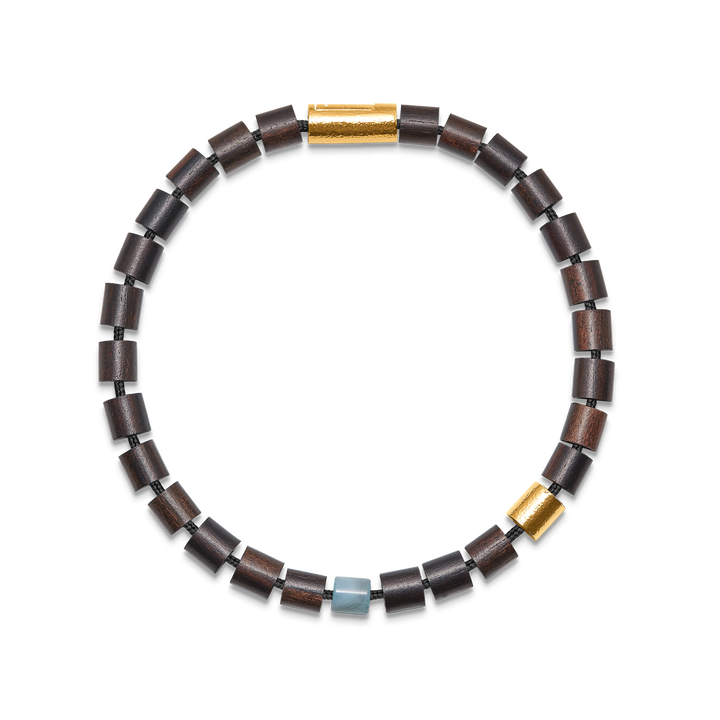 Armbånd med mørkebrune træperler, gulddetaljer og en lyseblå accentperle på sort baggrund. Model 12345