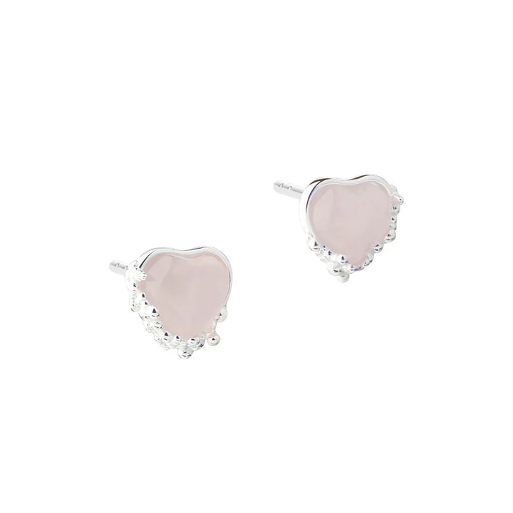 Hjärtformade örhängen i silver med rosa stenar, framifrån av smyckena i par