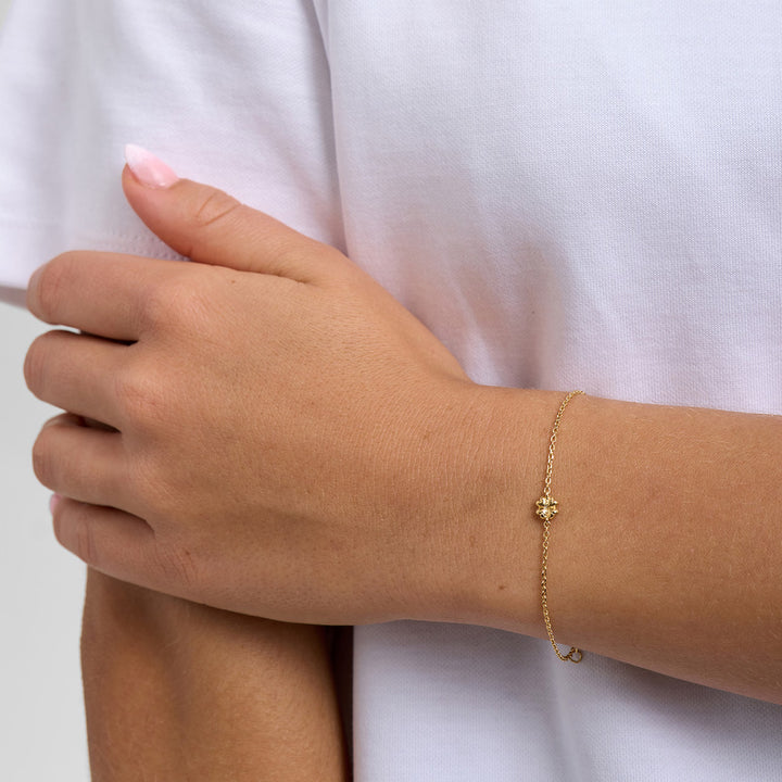 Blossom Copenhagen Carmen armbånd i guld med lille blomst, bæres på håndled. Model 7250359_1M