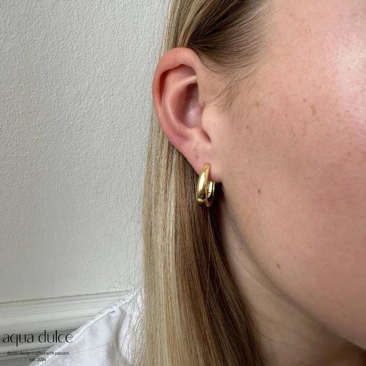 Aqua Dulce Big Emma Hoop silverpläterat örhänge visat på örat, glänsande guldfinish. Modell 5535-5535-2