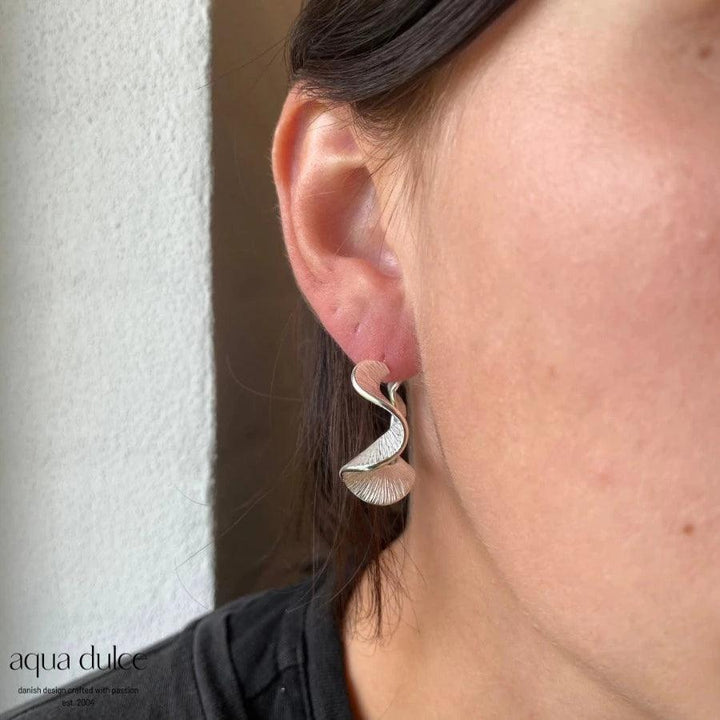 Aqua Dulce Rhumba Hoop Creole Silver visas på örat, elegant vriden båge i ljust silver. Modell 5099-5099-2