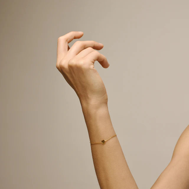 enamel-fyrklöver-armband-i-guldpläterad-sol bärs på handleden, tunt kedjearmband i guldlook med liten klöverdetalj. Modell b148gm-2