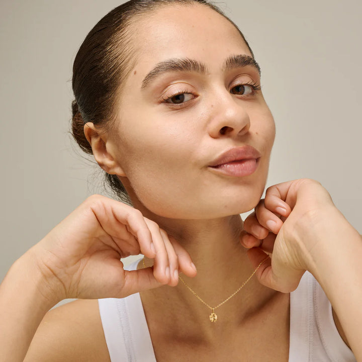 Enamel Four Leaf Clover-halsband i guldpläterat silver som bärs av kvinna med vit topp, modell n138gm-1