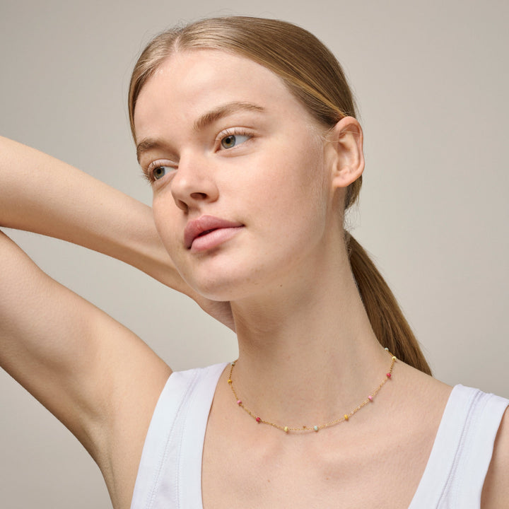 Enamel Lola Bold halsband Rainbow i guldpläterat silver med färgglada pärlor, bärs av modell. Modell n137g-rainbow-2