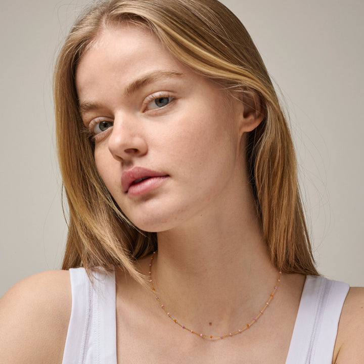 Enamel Lola halsbandsrouge i guldpläterat silver visat på modell, delikata rosa nyanser lyser lätt. Modell N55G-BLUSH-2