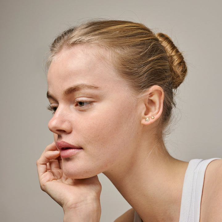 Enamel Mini Sunshine Stud Steel Blue visas på örat på en kvinna, små blåguld dubbar. Modell e419g-steelblue-2