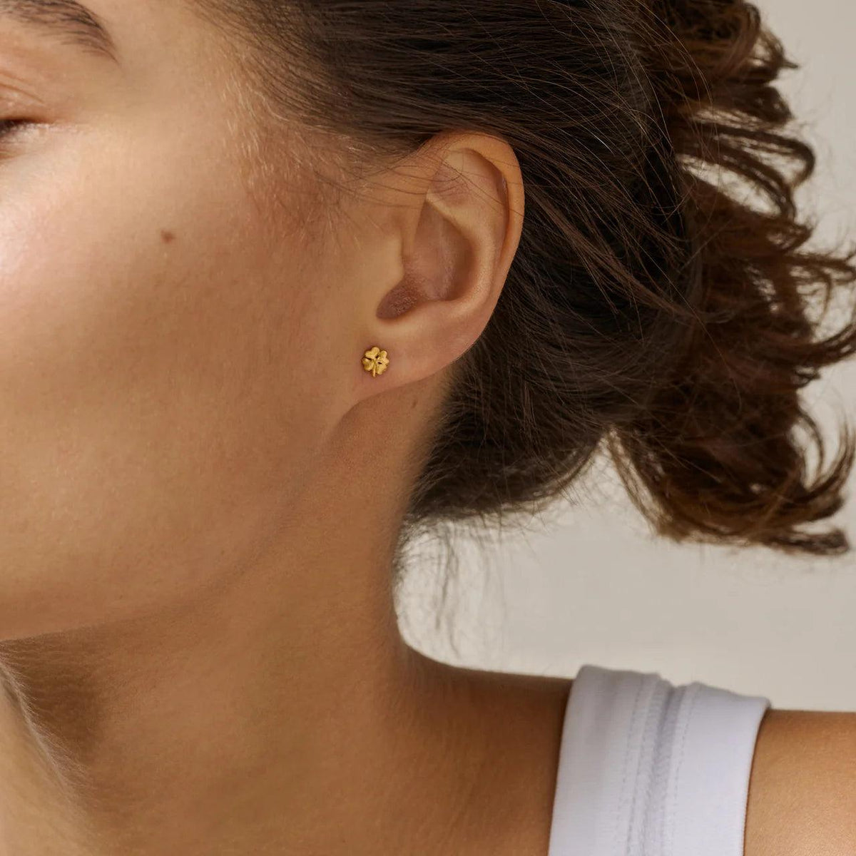 Enamel Organic Clover små fyrklöverdubbar i förgylld färg verkar bära på örat, modell E412GM-1.