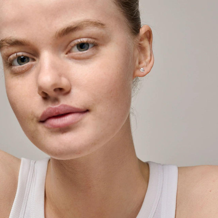 Enamel Organic Clover Small Four-Clover Örhängen i silver kan ses på örat av modellen, diskret design Modell e412sm