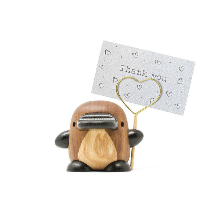 Fablewood Platypusen Perry visar en dekorativ träfigur i bruna nyanser med en metallskylt, modell 1403-2.