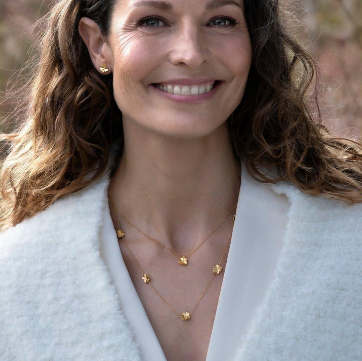 Flora Danica Fyrklöverhalsband med femklöver, bärs av kvinna, guldlook utomhus. Modell flc-nelo-g-2