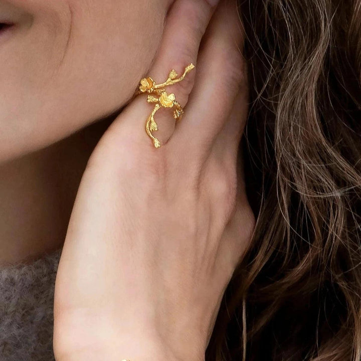 Flora Danica Forget-me-not Statement Ring visas till hands, i glansig guldton finish och blommig design. Modell FMN-STRI-G-001-2