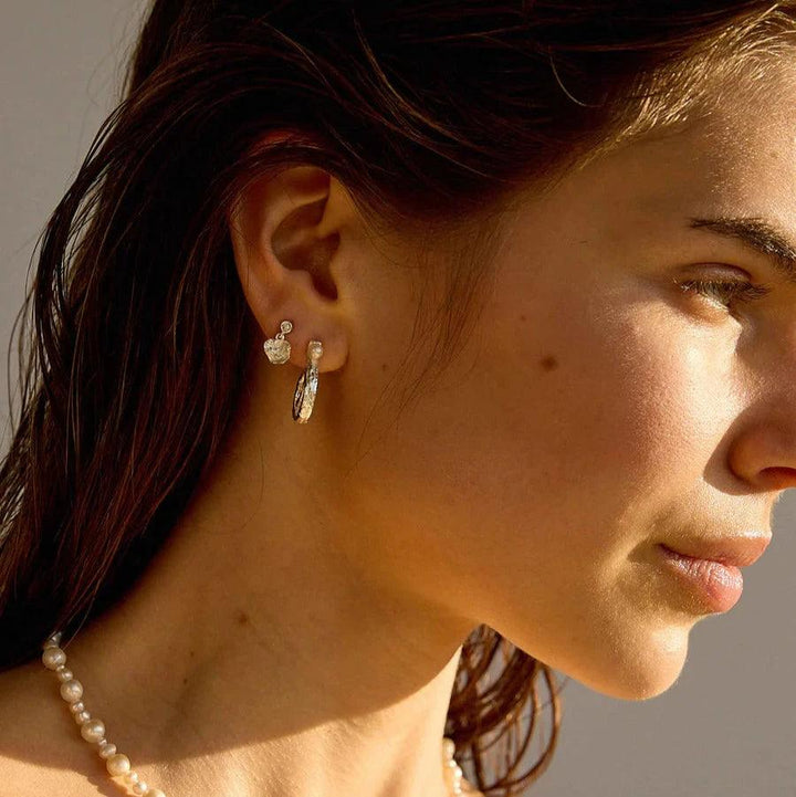 Hultquist Copenhagen Lainey Petite örhängen i silver som visas på modell med pärlkedja i solljus. Modell S08610S-2