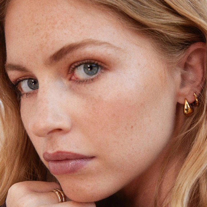 Jeberg Jewellry Audrey Drop-örhängen i guldfärgad metall på kvinna med ljust hår, modell 52920-1