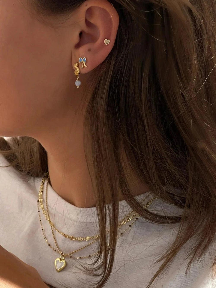 Jeberg Petite Bow blå örhängen med knoppar som visas på örat, blå rosett i förgylld design, modell 52810-2