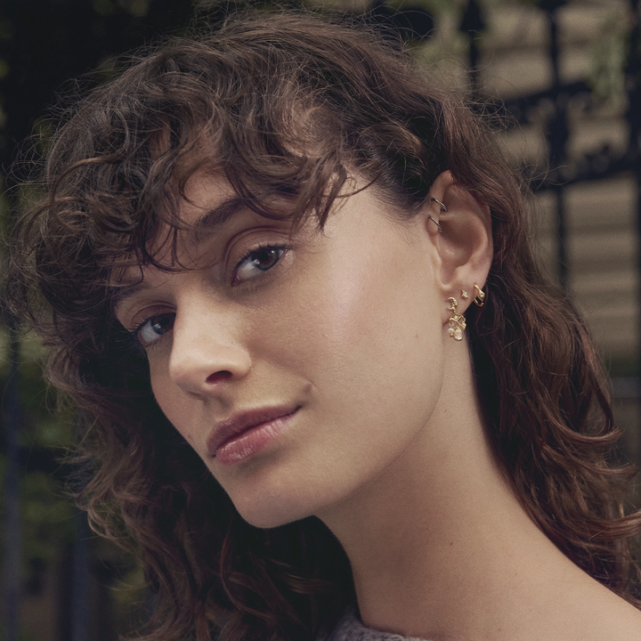 Maanesten Forte guldpläterade creoler i elegant blommig design bärs av modell, modell 10021a-2.