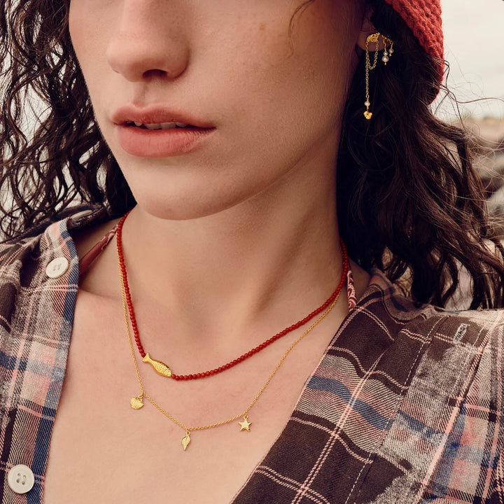 maanesten-iluka-halsband förgyllt med gyllene berlocker och röda pärlor, bärs av kvinna, modell 2818a-2