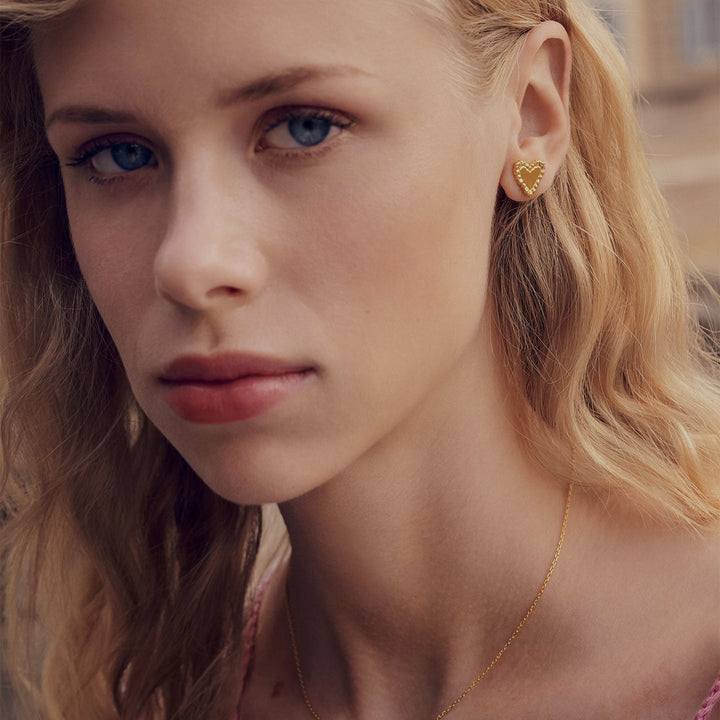 Maanesten Julie guldpläterade hjärtörhängen bärs av kvinnor, synliga detaljer och gyllene färg. Modell 10051a-2