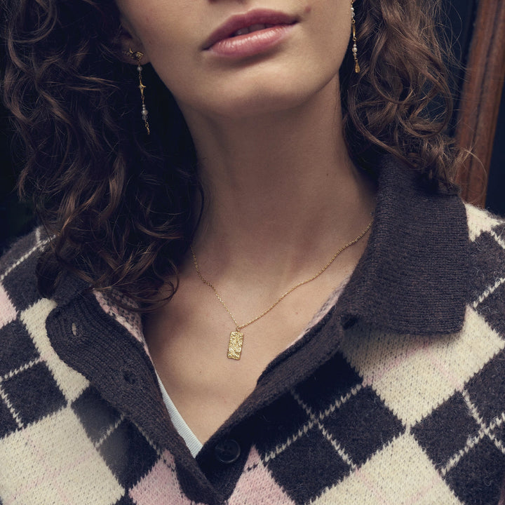 maanesten-notabene-guldpläterat-halsband bärs av kvinna, elegant fyrkantigt hänge i guld, modell 2802a-2