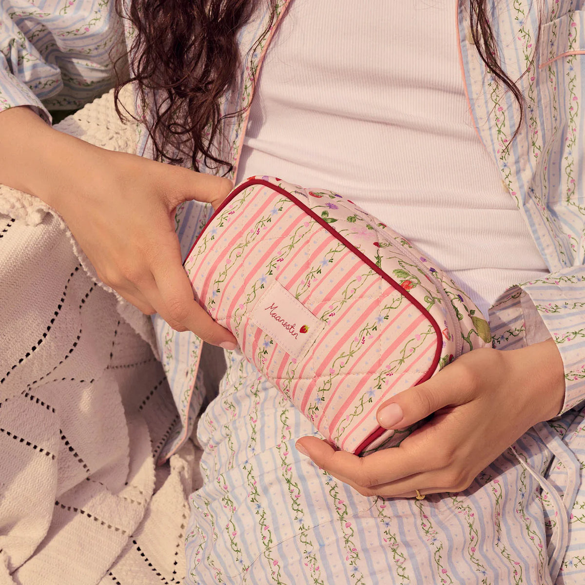 månsten-stjärndamm-påse-sommar-ränder-persika med rosa och grönrandiga blommönster hålls i knät. Modell 4114-onesize