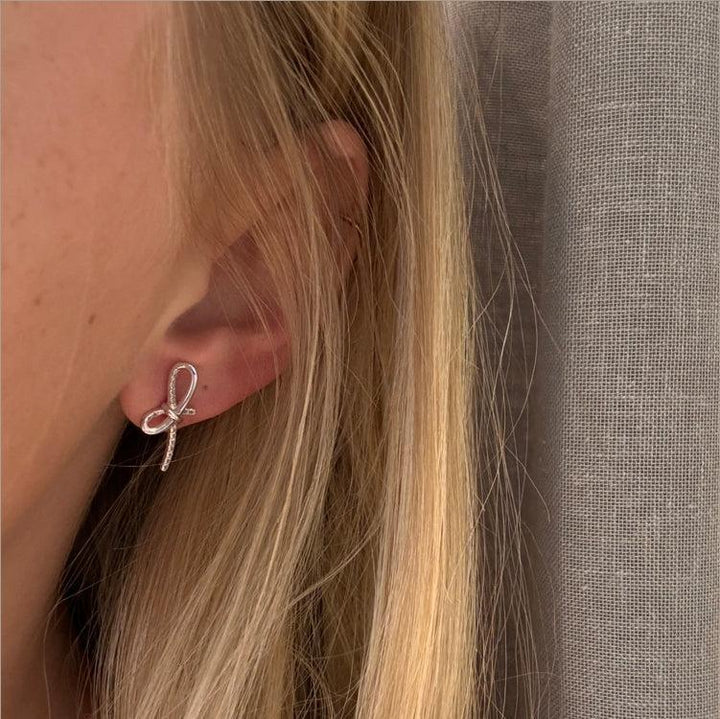 Mads Z Miss Butterfly rosettörhängen i silver med vit topas visas på örat. Modell 2116003-2