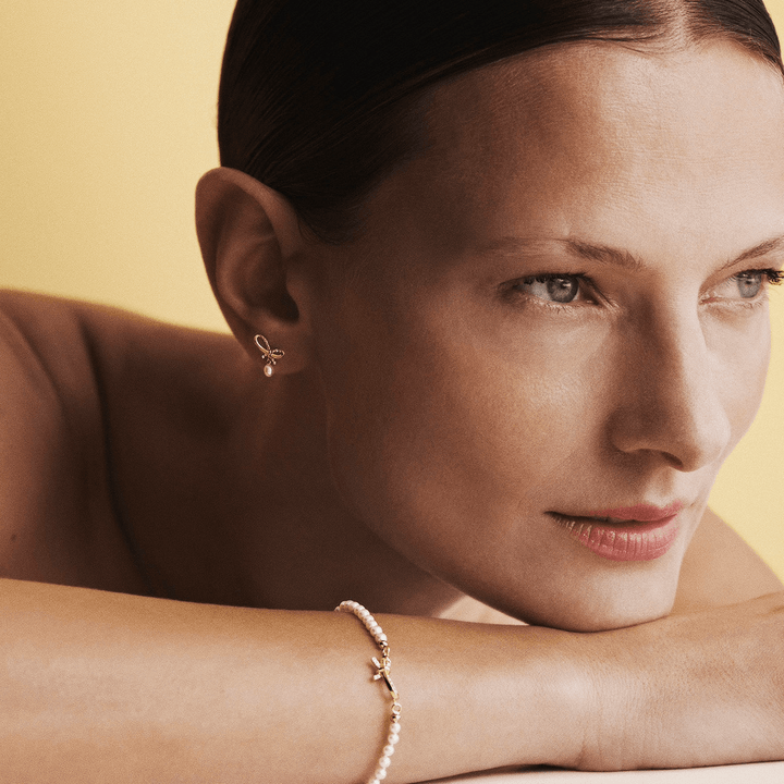 Mads Z Miss Butterfly Bow Pearl armband guld och diamanter, bärs av kvinna mot ljus bakgrund. Modell 1553030-2