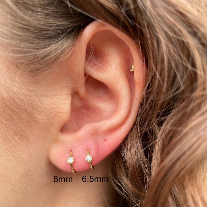 Maria Tash 8mm Scalloped Diamond Hoop Clicker visas i örat, guldfärgad och med diamantdetaljer. Modell xrscd-yg-d8-2.