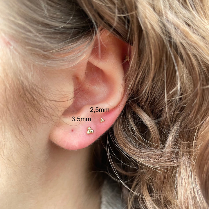 Maria Tash Ball Trinity Threaded Stud 2,5mm i guld, elegant detalj i örat på person, Modell xbtr-yg-w25-001-2