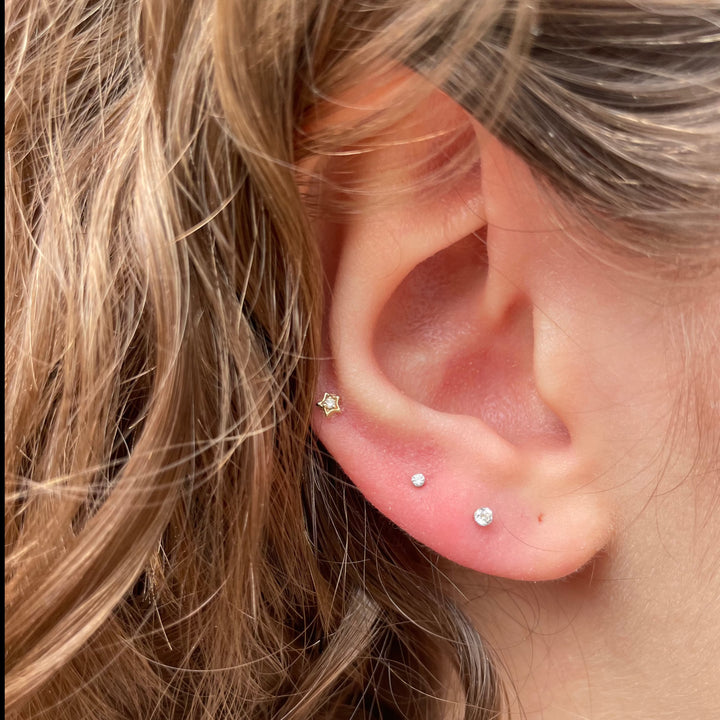 Maria Tash Diamond Solitaire Star vitguld XSSARD-WG-W3-001-2 visas placerad i örat, stjärnformad med diamantdetalj. Modell XSSARD-WG-W3-001-2