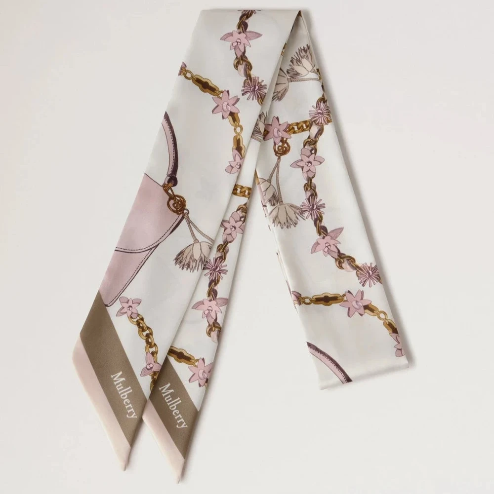 Mulberry Lana Bag and Chains Skinny Scarve Eggshell/Blossom Pink visar upp en smal sidenscarf med rosa och guldkedjedetaljer. Modell VS4849115W569