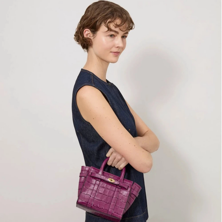 Mulberry Micro blixtlås Bayswater Orchid Bloom Shiny Small Croc visas bärs i handen på en kvinna. Modell RL8691641J512