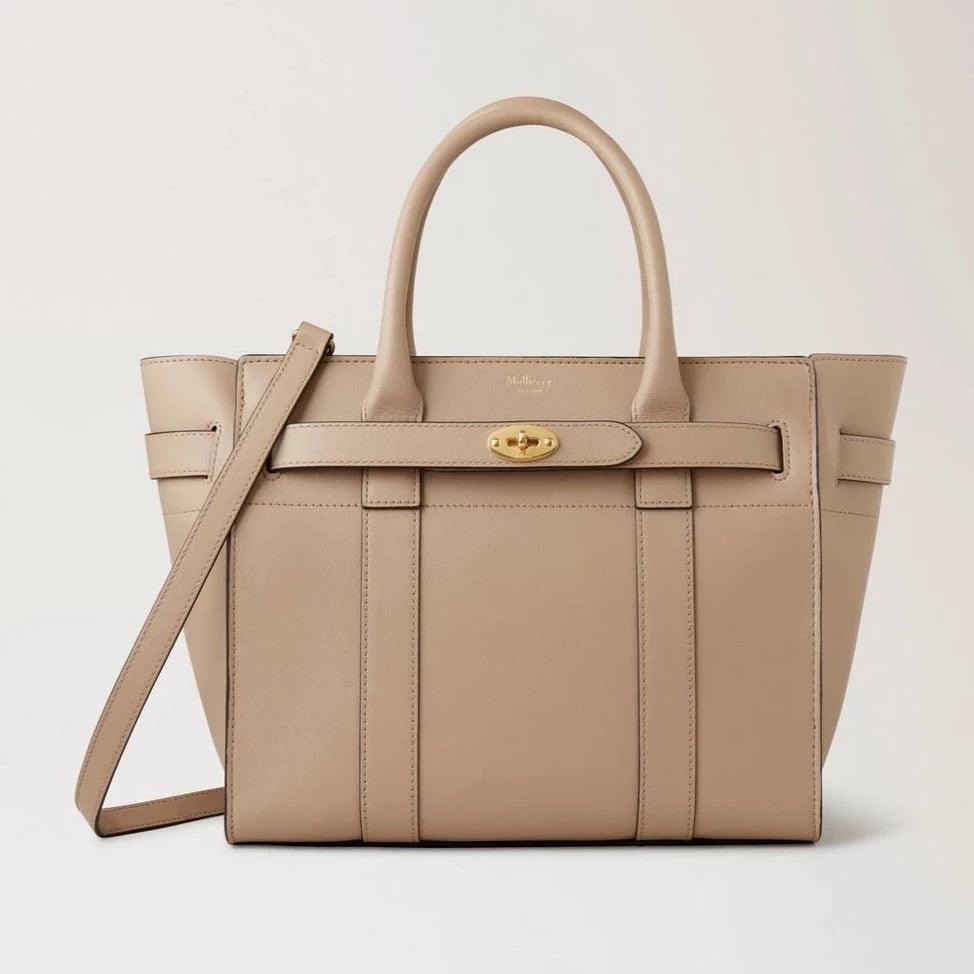 Mulberry Liten dragkedja Bayswater Maple Micro Grain visar upp en beige handväska i läder med gulddetaljer. Modell HH9066587E631.