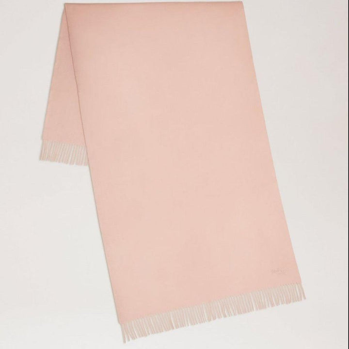 Mulberry Solid Merino Wool Scarf Rosewater visar upp en enkel, ljusrosa ullscarf med fransar. Modell VS4240947J633
