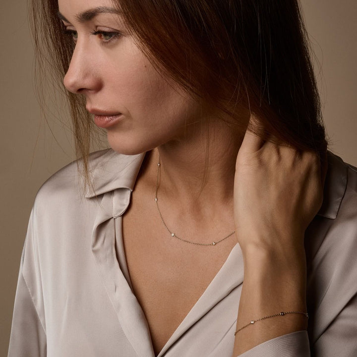 Nuran Zoe 14kt armband med diamanter bärs på handleden av kvinna i ljusbrun skjorta. Modell b1002-0125-2