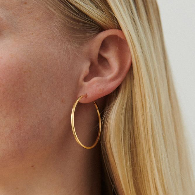 Pernille Corydon Small Orbit Hoops guldpläterade bärs på örat, smalt runt guldörhänge. Modell E-052-GP.