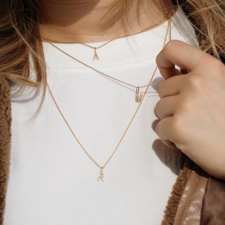 ro copenhagen min samling med diamanter, guldhalsband med bokstavshänge som bärs på vit blus, Modell p114y2-001-2