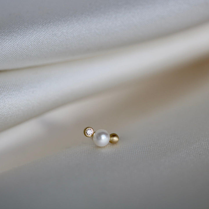 RO Copenhagen Orbit Dot WWF dubbar har en enda pärla, diamant och gulddetalj på ljust tyg. Modell E118Y103-2