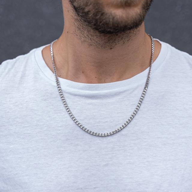 Son of Noa herrhalsband i silverfärgat stål, klassisk kedja, buren av man i vit t-shirt. Modell 80931002760.