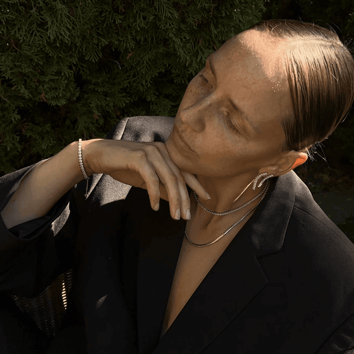 Studio Z Tennishalsband i guldpläterat silver som bärs av modellen utomhus med svart kavaj, modell 7227000-2.