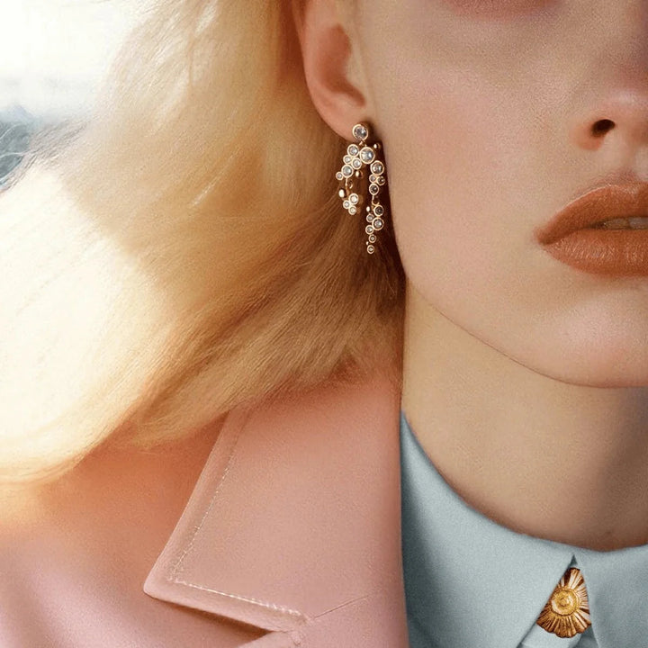 Vincent Lost Ember Guldpläterade örhängen som visas på modell med blont hår, elegant design med pärldetaljer. Modell VJ156-UEG-2