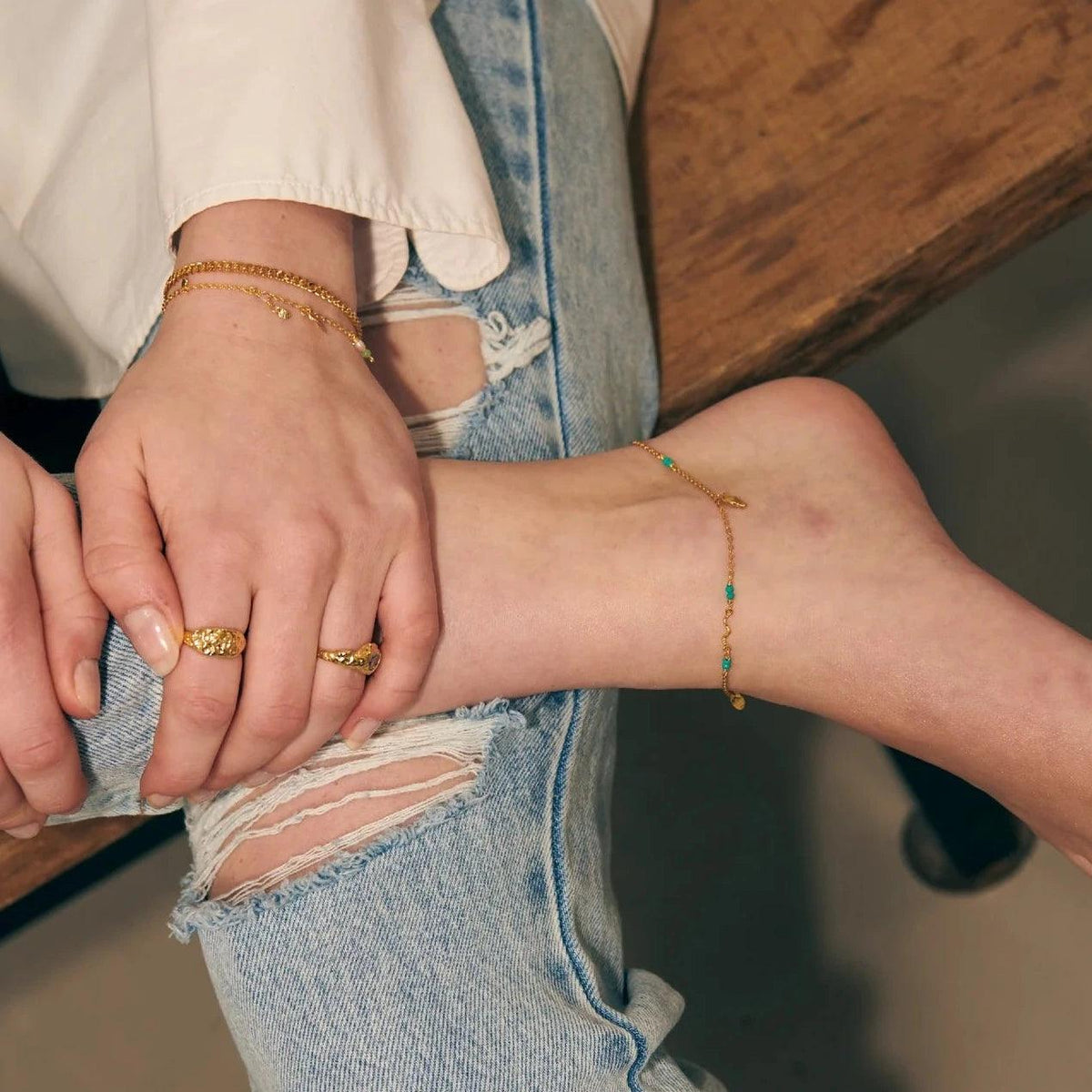 Wioga Octavia ankelkedja guldpläterad med turkos visad på ankeln, avslappnad stil. Modell A-8638-GP-1.