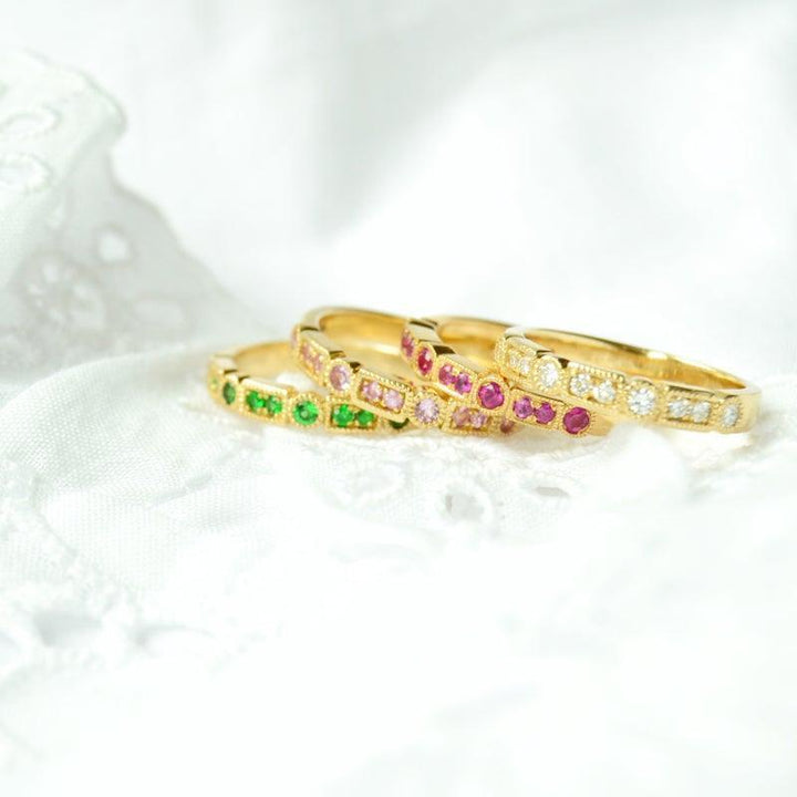 anpe-atelier-trine-ji-green-ring-14kt-guld-ringen ligger framtill, elegant med gröna stenar, i 14kt guld på vitt tyg. Modell 2500-001-2