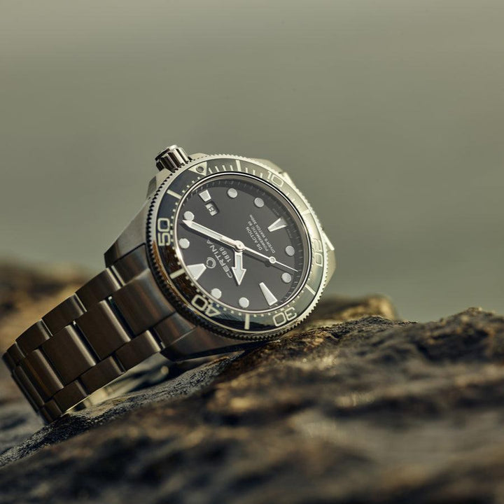 Certina DS Action Powermatic 80 herrklocka med svart urtavla och stålkedja på sten. Modell C0326071105100