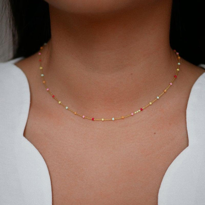 Enamel Lola Gilded Necklace N55G Rainbow, fin kedja med små färgade pärlor på modellen. Modell N55G-RAINBOW