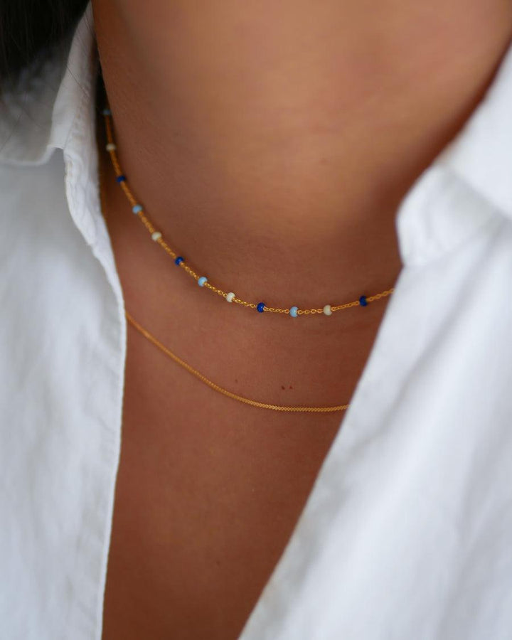 enamel lola halsband marin n55g visas på halsen, guldkedja med små blå och vita pärlor. Modell n55g-marine-n55g-marine-2