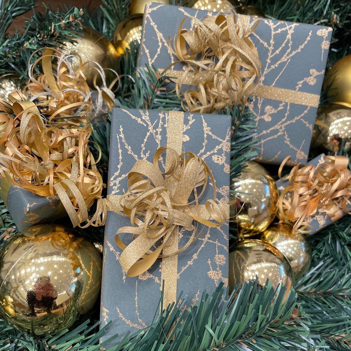 gratis-inpackning-julklappar--1, presentaskar i mörkt papper med gyllene band omgivna av juldekorationer. Modell gratis-inpackning-julklappar--1
