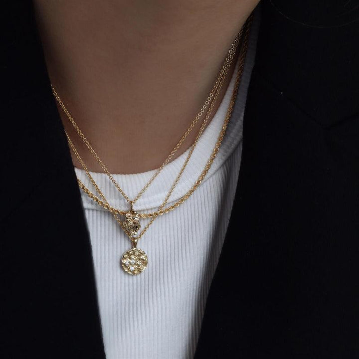 Jeberg Jewellery I Am Gold Petite Necklace bärs runt halsen med ett runt, mönstrat hänge i guld. Modell 40760-2