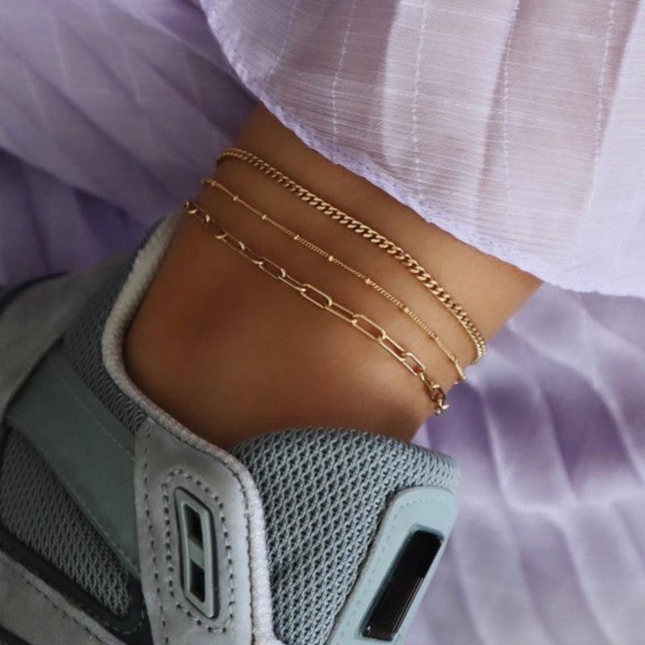 Jeberg Jewellery Saga Paner Vristlänk i guldpläterat silver visas på ankeln tillsammans med andra kedjor. Modell 4535-G-4535-G-2