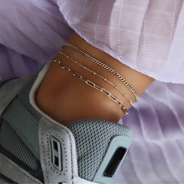 jeberg-smycken-sophia-solv-anklekaede visar en ankellänk i silver på en ankel med sneaker och ljuslila tyg. Modell 4550-S-2