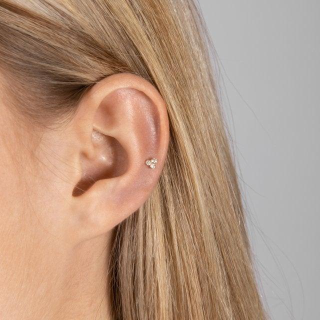 Nordahl 14kt guldpiercing 0,04ct visas på ett öra med ljust hår, liten elegant design. Modell 314007br5